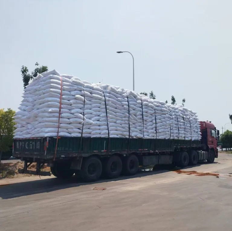 Finished packages of tofu cat litter being packed into large white woven sacks for the most cost-effective, high-volume bulk shipping method.
